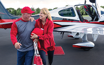 A happy couple beside a cirrus aircraft plane