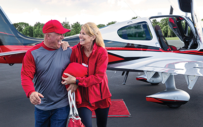 A man and woman in front of a cirrus aircraft