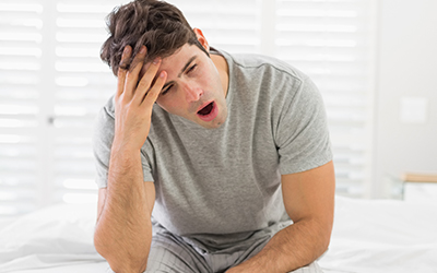 An older man sitting down and yawning